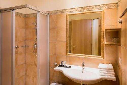 a bathroom with a sink and a shower with a mirror at Hapimag Ferienwohnungen St Michael in Sankt Michael im Lungau