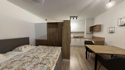 a bedroom with a bed and a table and a kitchen at 1 room Apartment with terrace, Petržalka in Bratislava