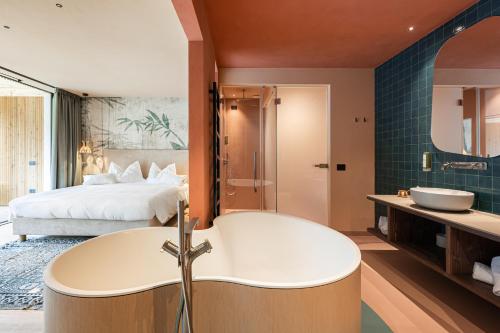 un bagno con vasca e una camera con letto di Latemar - Hotel Suites Spa a Soraga