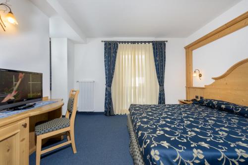 a hotel room with a bed and a flat screen tv at Family Hotel Andes - Only for Family in Vigo di Fassa