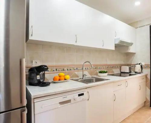 a kitchen with a sink and a bowl of oranges at Centro Playa de Sabinillas Manilva in San Luis de Sabinillas