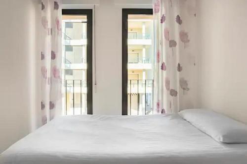 a white bed in a room with a window at Centro Playa de Sabinillas Manilva in San Luis de Sabinillas