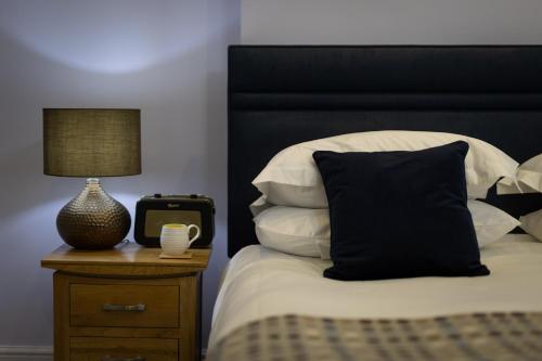 Una cama con cabecero negro y una mesa con reloj. en Caemorgan Mansion en Cardigan