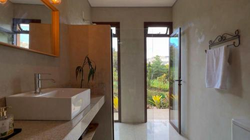 La salle de bains est pourvue d'un lavabo blanc et d'une douche. dans l'établissement Chalé Aurora da Serra - Lapinha da Serra, à Santana do Riacho