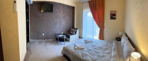 a bedroom with a bed and a chair and a window at Complex MONACO HOTEL & CASINO in Svilengrad