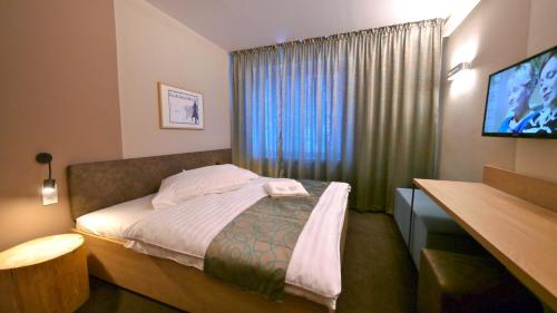 a hotel room with a bed and a television at Riverside in Demanovska Dolina