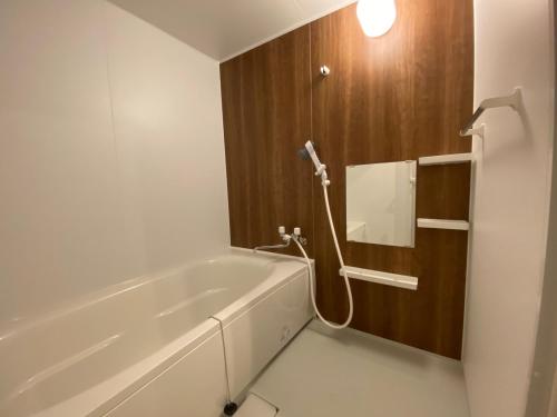 La salle de bains est pourvue d'une baignoire et d'un miroir. dans l'établissement Osaka Ukiyoe Ryokan, à Osaka