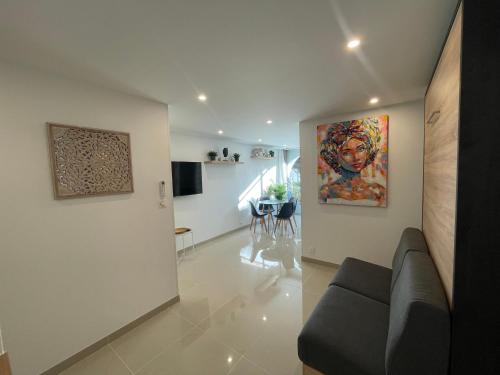 a living room with a couch and a painting on the wall at Grand studio en centre ville et à 50 mètres du port, climatisé in La Grande Motte