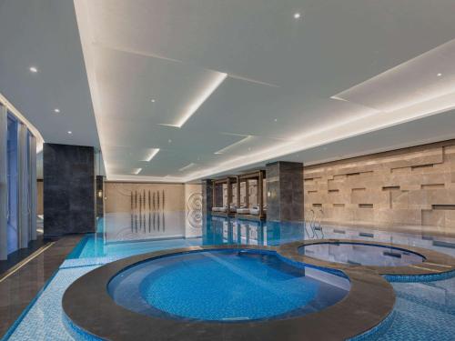 a swimming pool in a building with a large blue pool at Pullman Huai'an 淮安铂尔曼酒店 in Huai'an