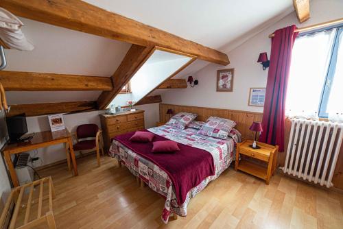 a bedroom with a bed and a desk and a window at Hotel Restaurant La Source in La Foux