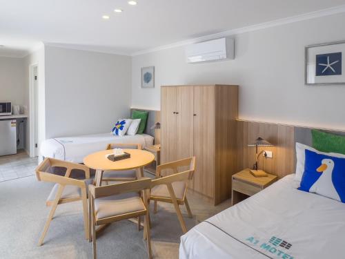a hotel room with two beds and a table and a desk at A1 Motels and Apartments Port Fairy in Port Fairy