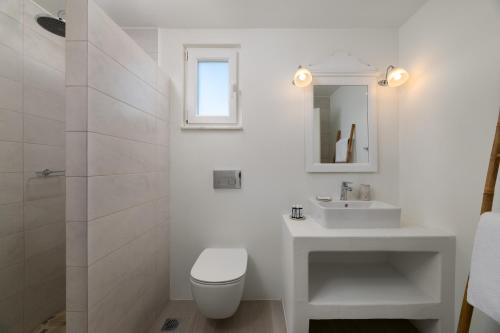 uma casa de banho branca com um WC e um lavatório em Stegna Akti Luxury Suites em Archangelos