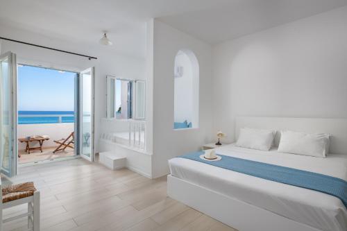 una camera bianca con letto e vista sull'oceano di Stegna Akti Luxury Suites a Archangelos