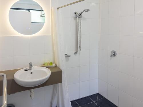 a white bathroom with a sink and a shower at A1 Motels and Apartments Port Fairy in Port Fairy