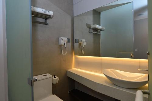 a bathroom with a sink and a mirror at Rume Hotel in Kuching