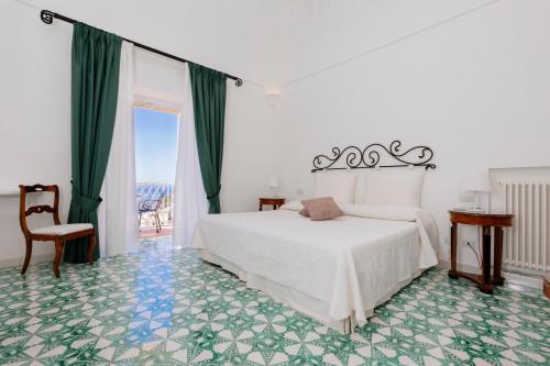 1 dormitorio con 1 cama blanca y suelo verde en La Bizantina Luxury Villa, en Positano