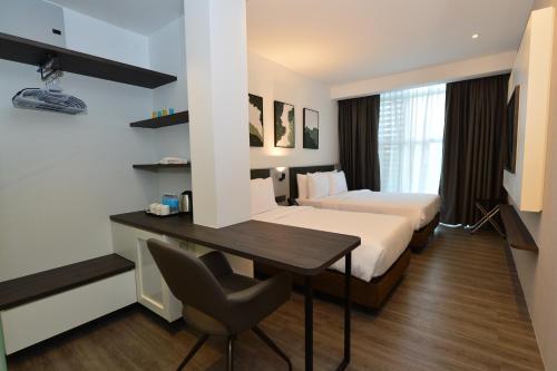 Habitación de hotel con cama, escritorio y mesa. en Rume Hotel en Kuching