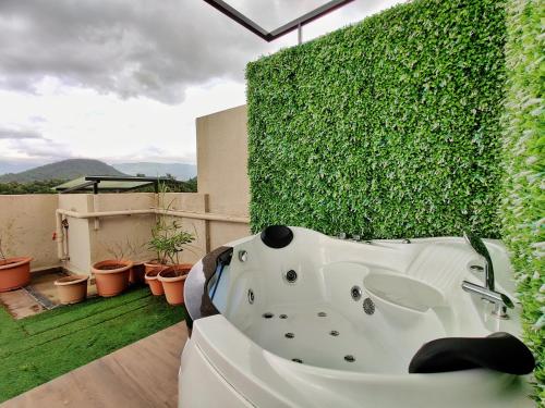 a bath tub sitting on a balcony with a green wall at Pushpam Sanskruti Resort Karjat- Pure Veg in Karjat
