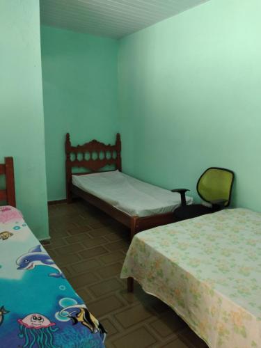 pokój z 2 łóżkami i krzesłem w obiekcie Pedacinho do Paraiso w mieście Mongaguá