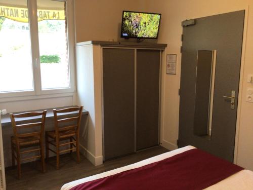 1 dormitorio con 1 cama y TV encima de un armario en Hôtel Bellevue Bagnoles Normandie, en Bagnoles de l'Orne