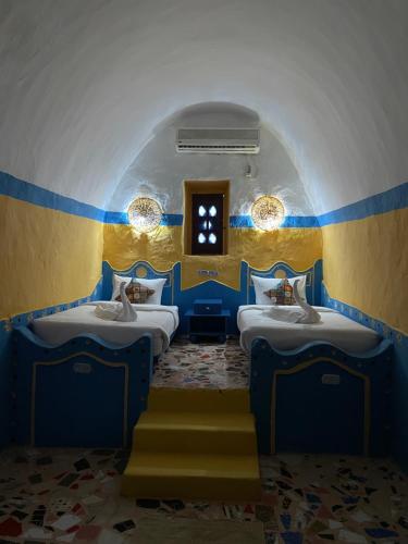 アスワンにあるNubian palaceの青と黄色の部屋 ベッド3台付