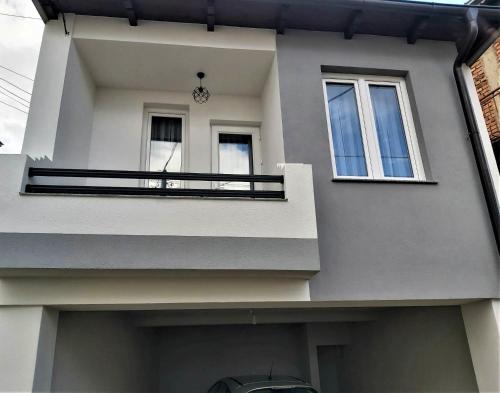 a white house with a balcony and two windows at Studio Apartment - Prizren in Prizren