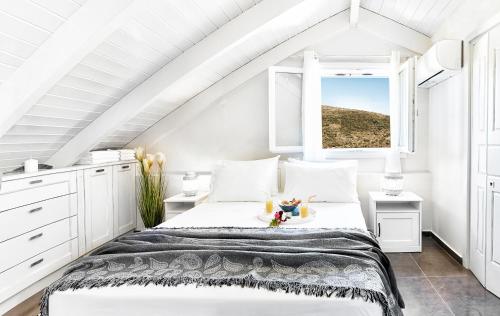 een witte zolderslaapkamer met een bed en een raam bij Villa Iremia in Platithriás