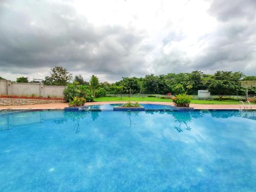 a large swimming pool with blue water at Pushpam Sanskruti Resort Karjat- Pure Veg in Karjat