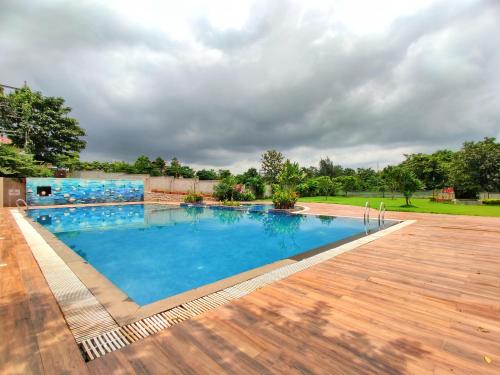 a large swimming pool with a wooden floor and a wooden deck at Pushpam Sanskruti Resort Karjat- Pure Veg in Karjat