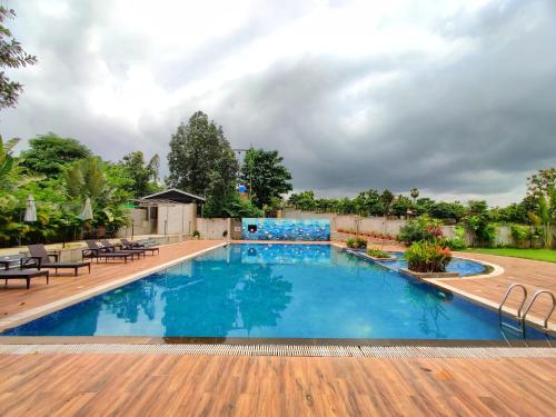 a large swimming pool with a wooden deck at Pushpam Sanskruti Resort Karjat- Pure Veg in Karjat