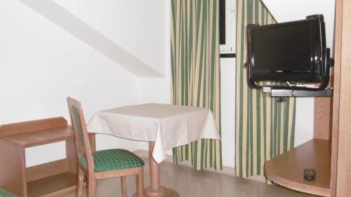 Hotel Riviera في أرنزانو: طاولة صغيرة مع كرسي وتلفزيون في الغرفة