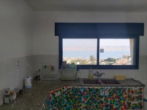 turtle guesthouse- tiberias في طبرية: مطبخ مع نافذة وطاولة مع حوض