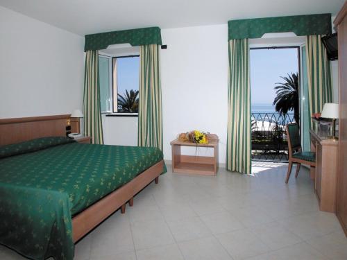 a bedroom with a green bed with a view of the ocean at Hotel Riviera in Arenzano