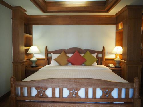 a bedroom with a large bed with four pillows at Rich Lanna House in Chiang Mai