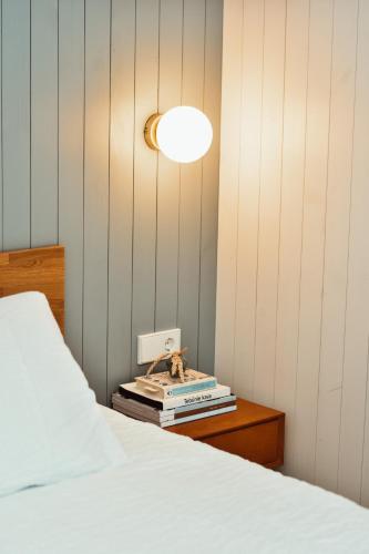 a bedroom with a bed with a lamp and books at Poilsio nameliai - B E L A I K O in Kretinga
