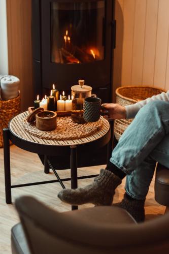 a person sitting in a chair with a table with candles at Poilsio nameliai - B E L A I K O in Kretinga