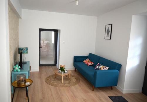 a living room with a blue couch and a table at Logement Cosy à 5mn du Futuroscope in Jaunay-Marigny