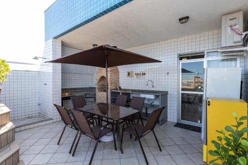 a table and chairs with an umbrella on a patio at Cobertura de alto padrão com vista para a Praia do Forte in Cabo Frio