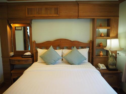 a bedroom with a large bed with a wooden headboard at Rich Lanna House in Chiang Mai