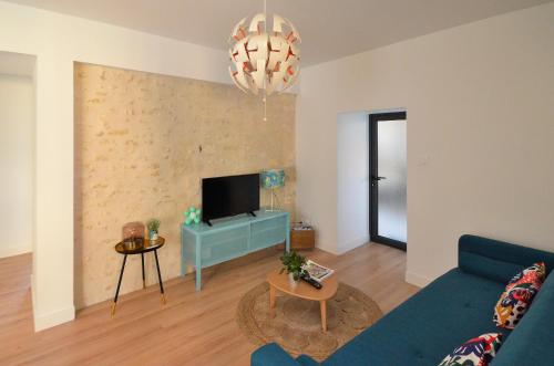 a living room with a blue couch and a tv at Logement Cosy à 5mn du Futuroscope in Jaunay-Marigny