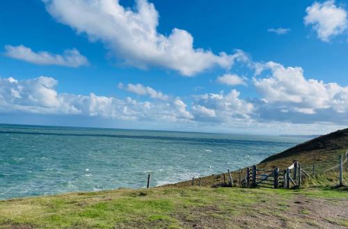 a fence on a hill next to the ocean at Caemorgan Mansion in Cardigan