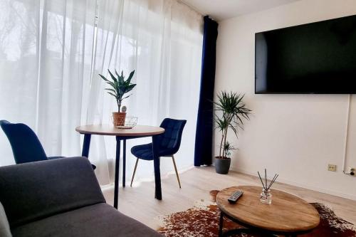 een woonkamer met een tafel en een televisie bij Schönes Apartment in Erkrath, Nähe Düsseldorf in Erkrath