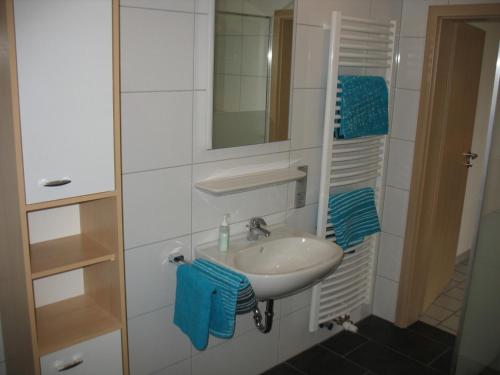 a bathroom with a sink and a mirror and blue towels at Haus Eichengrund in Papenburg