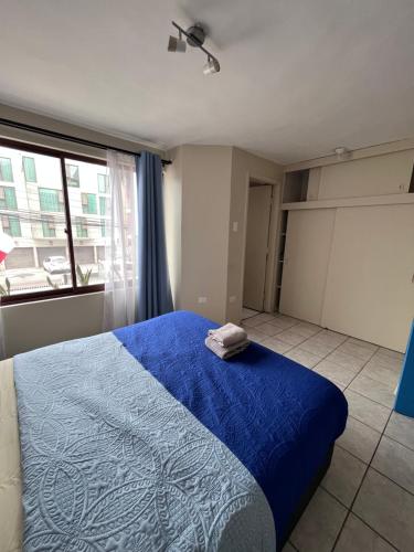 um quarto com uma cama azul e uma janela em 3D 2B cerca playa y centro, Park Surf em Iquique