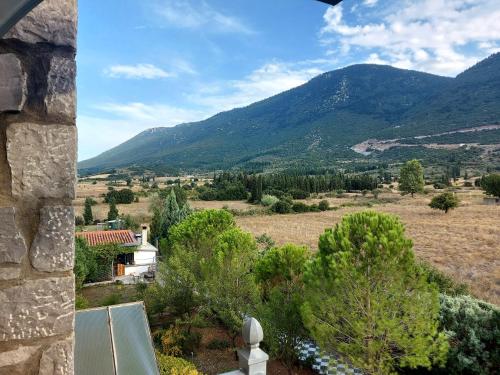 a view of a valley with a house and mountains at Xenios Petritis in Levádeia