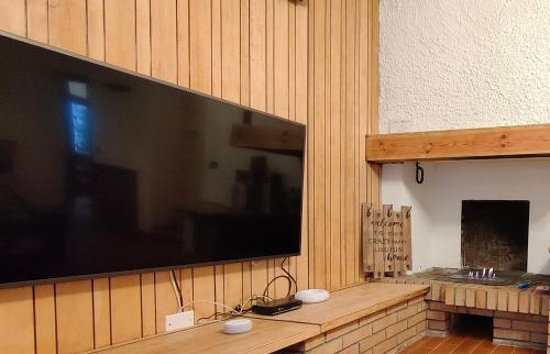 a large flat screen tv on a wooden wall at Chalet Bornhome relax, sport e cultura altopiano del sole 6 ospiti - pet Frendly in Borno