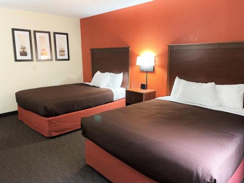 two beds in a hotel room with orange walls at AmericInn by Wyndham Petoskey in Petoskey