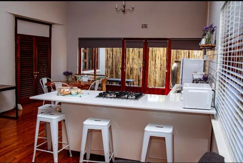 a kitchen with a counter with stools and a sink at The Grey House in Beaufort West