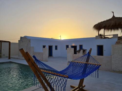 a blue hammock sitting on a patio next to a pool at Houche djerbien in Mezraya