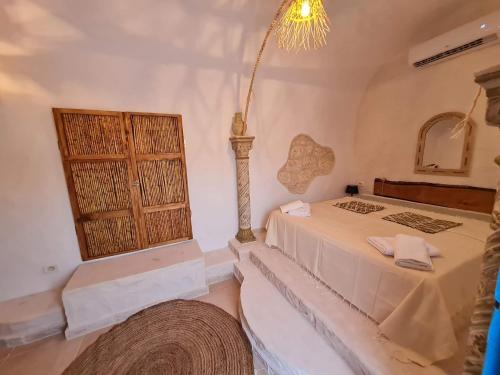 a bedroom with a bed and a window and a chandelier at Houche djerbien in Mezraya
